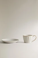 STONEWARE TEACUP AND SAUCER WITH RAISED DESIGN