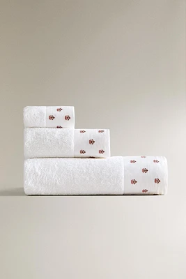 TOWEL WITH EMBROIDERED SASH APPLIQUÉ