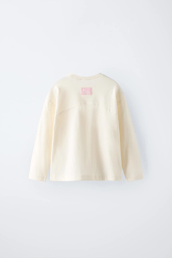 T-shirt with round neck and long sleeves. Label appliqué at back hem.