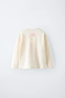 T-shirt with round neck and long sleeves. Label appliqué at back hem.