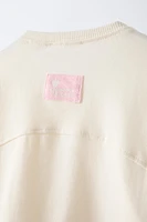 T-shirt with round neck and long sleeves. Label appliqué at back hem.