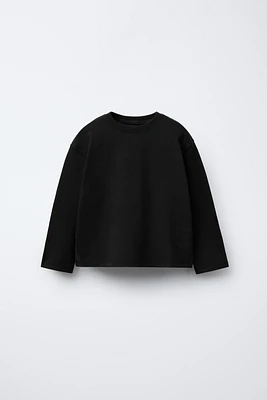 T-shirt with round neck and long sleeves. Label appliqué at back hem.