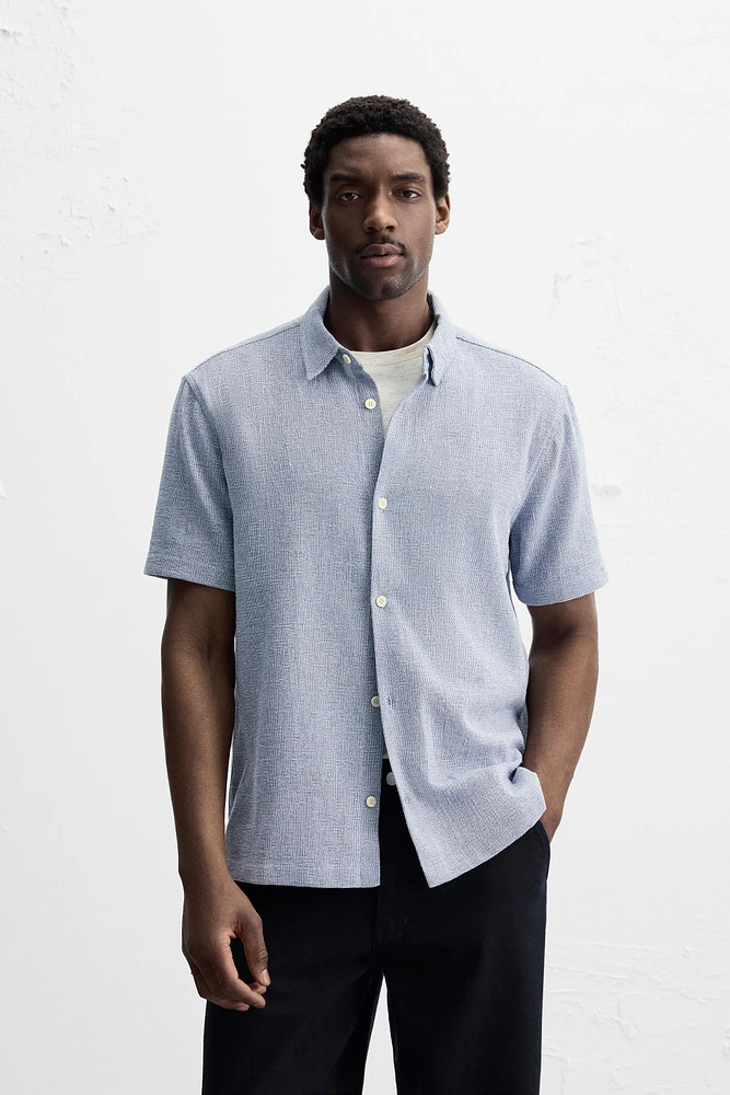 Relaxed fit shirt made of cotton blend fabric. Lapel collar and short sleeves. Side vents at hem. Front button closure.