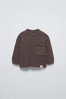 Sweater with round neck and long sleeves cuffs. Back button closure. Patch pocket at chest. Label appliqué hem.