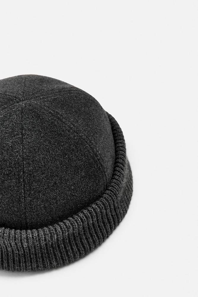 Hat made of tonal matching fabrics with turned-up knit brim. Adjusts loop.