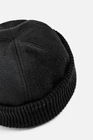 Hat made of tonal matching fabrics with turned-up knit brim. Adjusts loop.