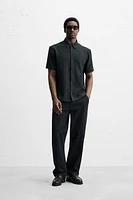 Relaxed fit shirt made of cotton blend fabric. Lapel collar and short sleeves. Side vents at hem. Front button closure.