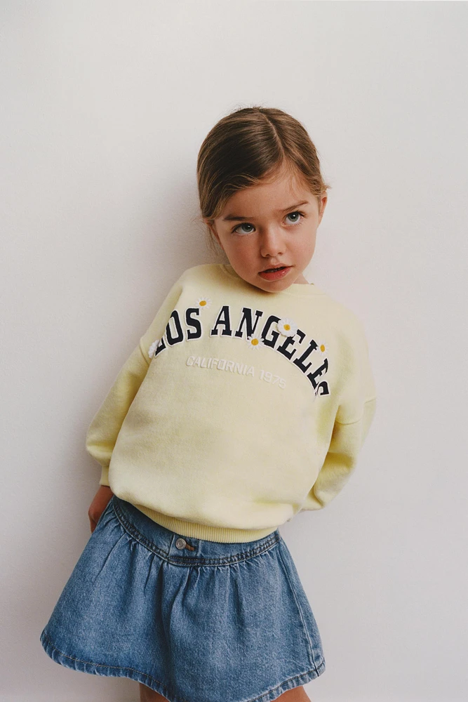 RAISED TEXT DAISY SWEATSHIRT