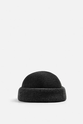 Hat made of tonal matching fabrics with turned-up knit brim. Adjusts loop.