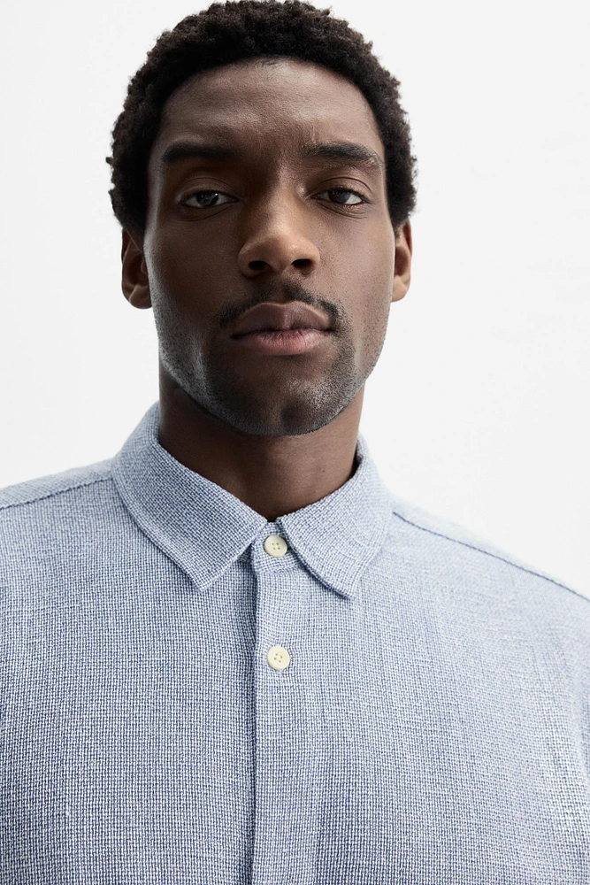 Relaxed fit shirt made of cotton blend fabric. Lapel collar and short sleeves. Side vents at hem. Front button closure.