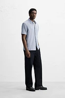 Relaxed fit shirt made of cotton blend fabric. Lapel collar and short sleeves. Side vents at hem. Front button closure.