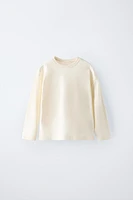 T-shirt with round neck and long sleeves. Label appliqué at back hem.