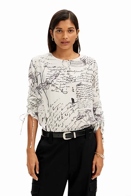 Blusa com textos e mangas ajustáveis.